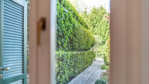 A pathway flanked by neatly trimmed hedges and a small potted plant. - Solelago by Wonderful Italy (San Siro)