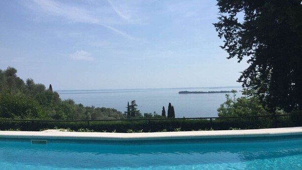 A clear blue pool with a view of the sea and a distant island.