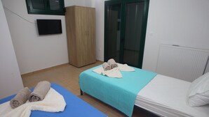 Une petite pièce propre, avec un lit, un tapis bleu et une armoire en bois.