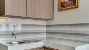 A kitchen with striped tile backsplash, a stainless steel sink, and wooden cabinets. - OYO Life 90211 I-sidji Inn (Karawang)