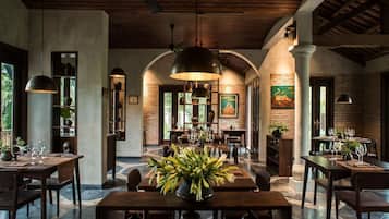 A spacious dining area with high ceilings, exposed brick walls, and a central table with a floral arrangement.