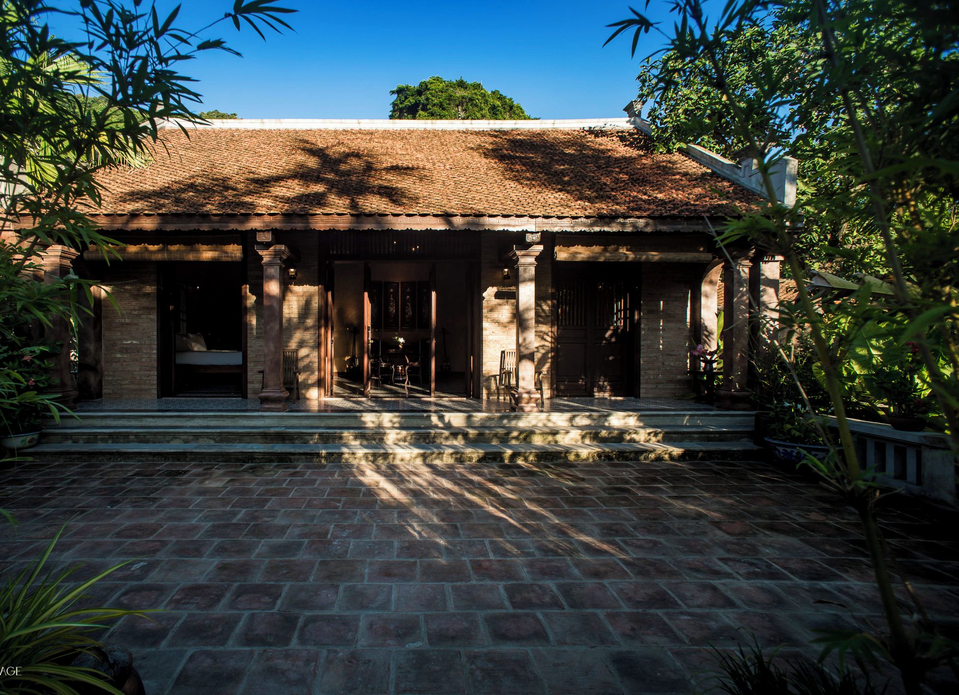 A traditional building with a tiled roof, columns, and a stone-paved courtyard.