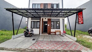 A modern building with a covered entrance, a motorcycle parked outside, and a signboard. - Hotel O Marta Residence (Karawang)
