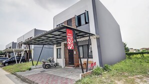 A modern building with a covered entrance, a red banner, and a parked scooter. - Hotel O Marta Residence (Karawang)