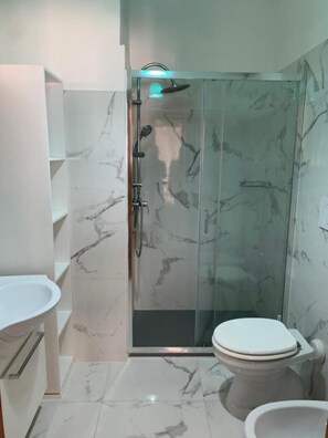 Ein Badezimmer mit Duschkabine, Toilette und Waschbecken.