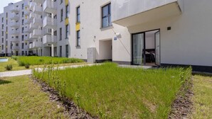 Een modern appartementencomplex met balkons, een gazon en een heldere lucht.