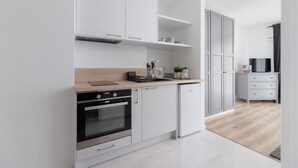 Een moderne keuken met witte kastjes, een inbouwoven en een houten aanrecht.