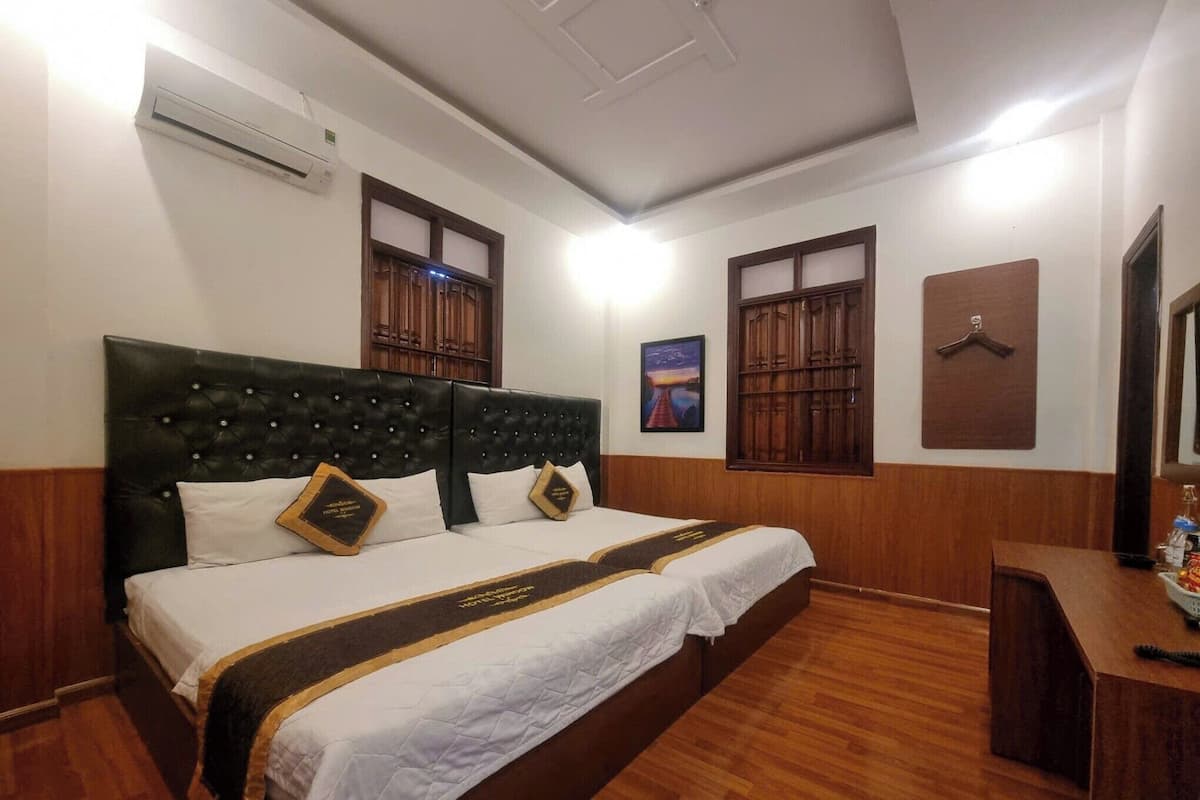 A hotel room with a large bed, wooden headboard, and a desk with a telephone.