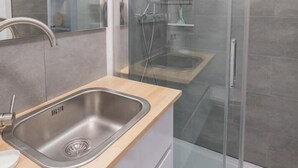 Un bagno moderno con doccia vetrata, lavandino in acciaio inox e specchio.