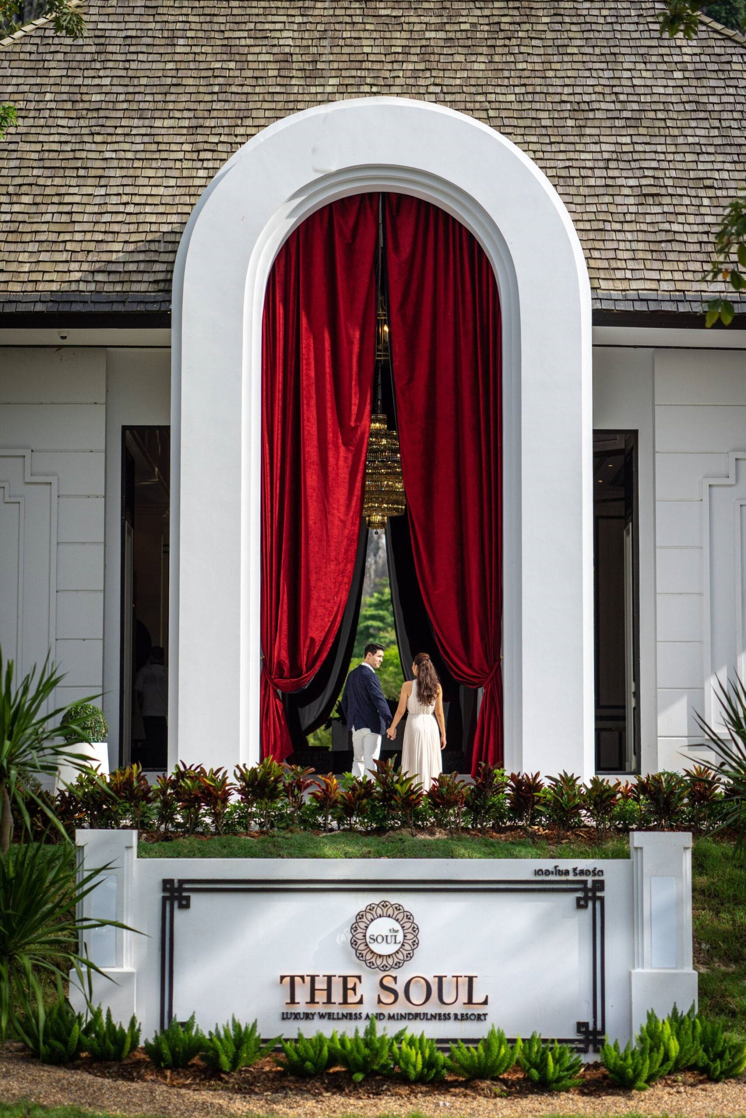 A sign for "The Soul Luxury Wellness and Mindfulness Resort" with a white building and red curtains.