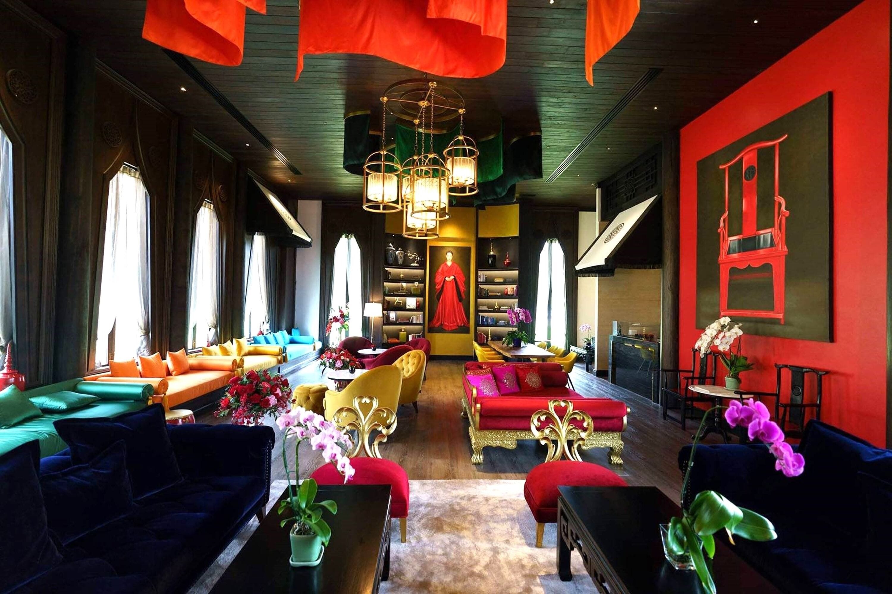 A spacious, elegantly furnished lounge with a central seating area, large windows, and a striking red accent wall.