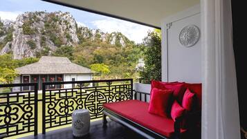 Uma varanda com um sofá vermelho, um vaso decorativo e vista para uma montanha.