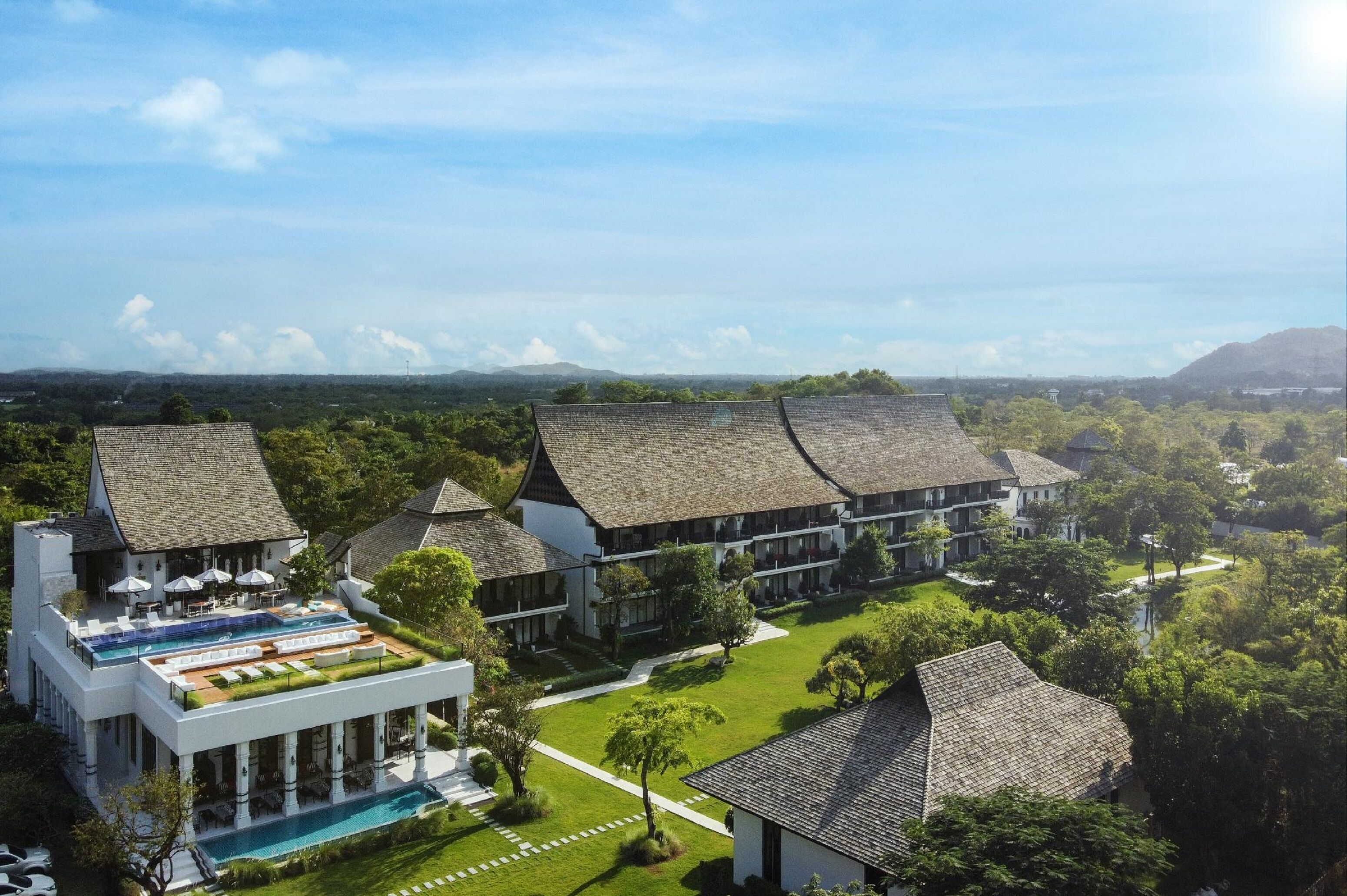 A resort with multiple buildings, a swimming pool, and lush greenery.