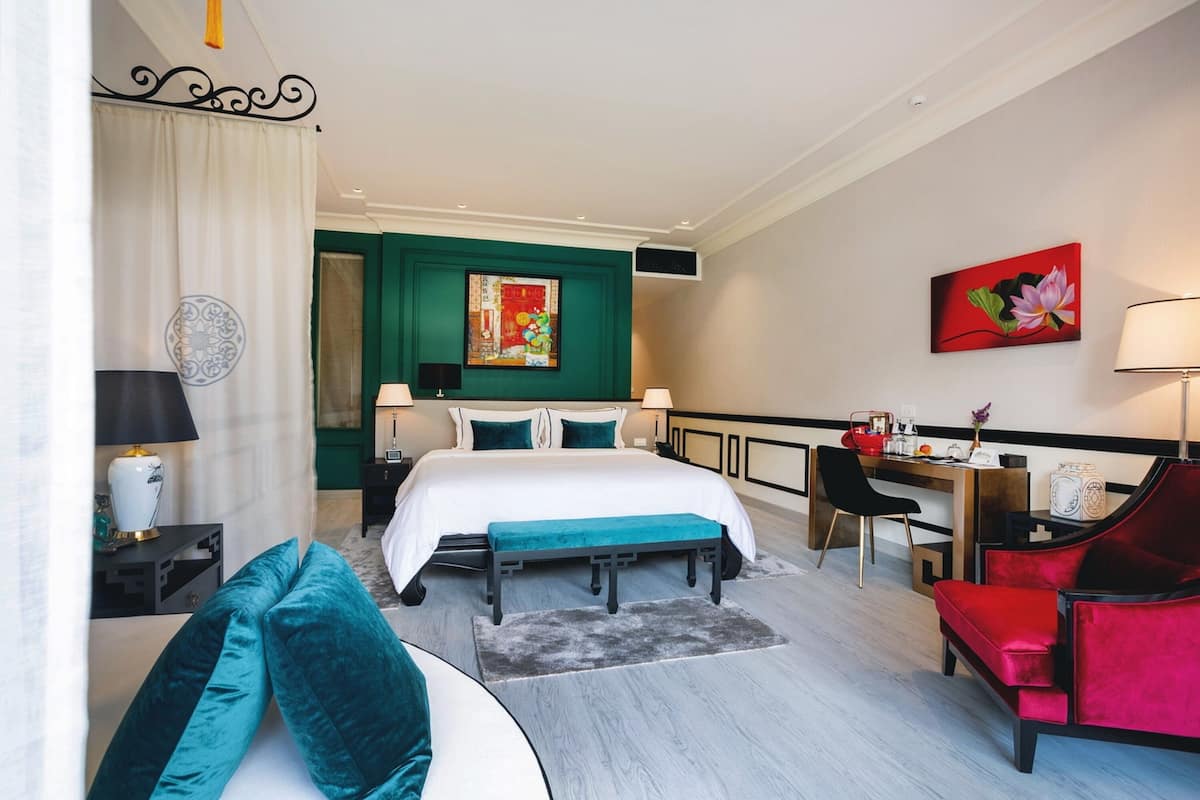 A hotel room with a bed, a desk, a chair, and a sofa.