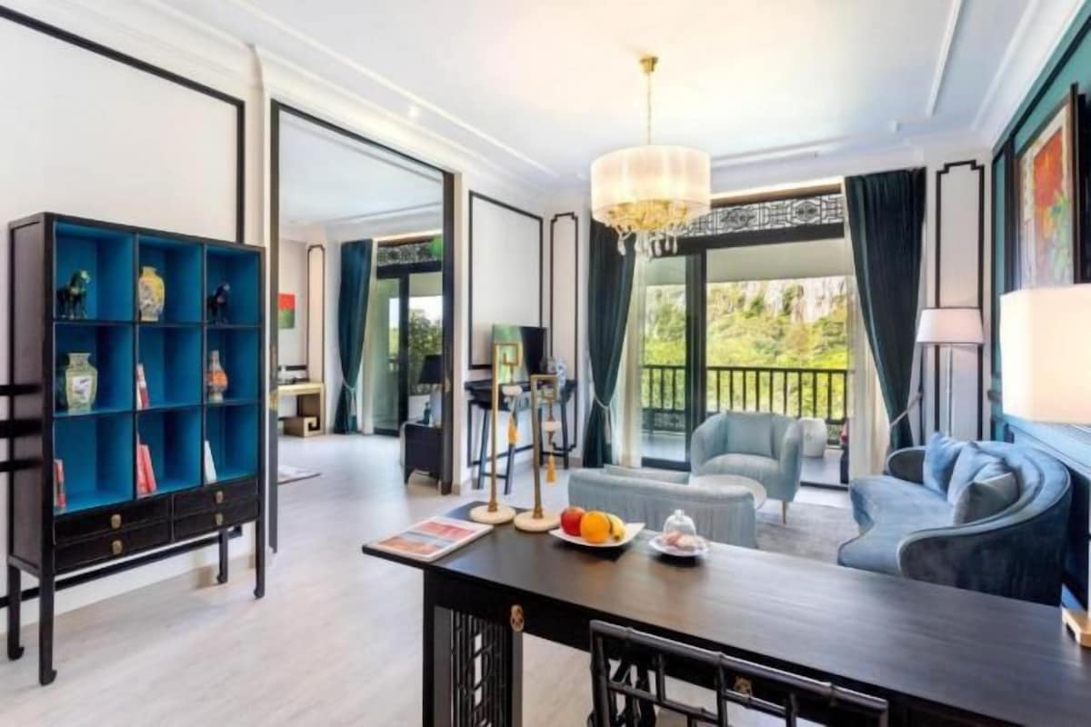 Una sala de estar moderna con comedor, una estantería azul y un amplio ventanal con vistas a zonas verdes.