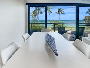 Une chambre moderne dotée d’une grande fenêtre donnant sur une plage et des palmiers.