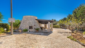 A stone building with a circular structure, a covered patio, and a paved entrance.