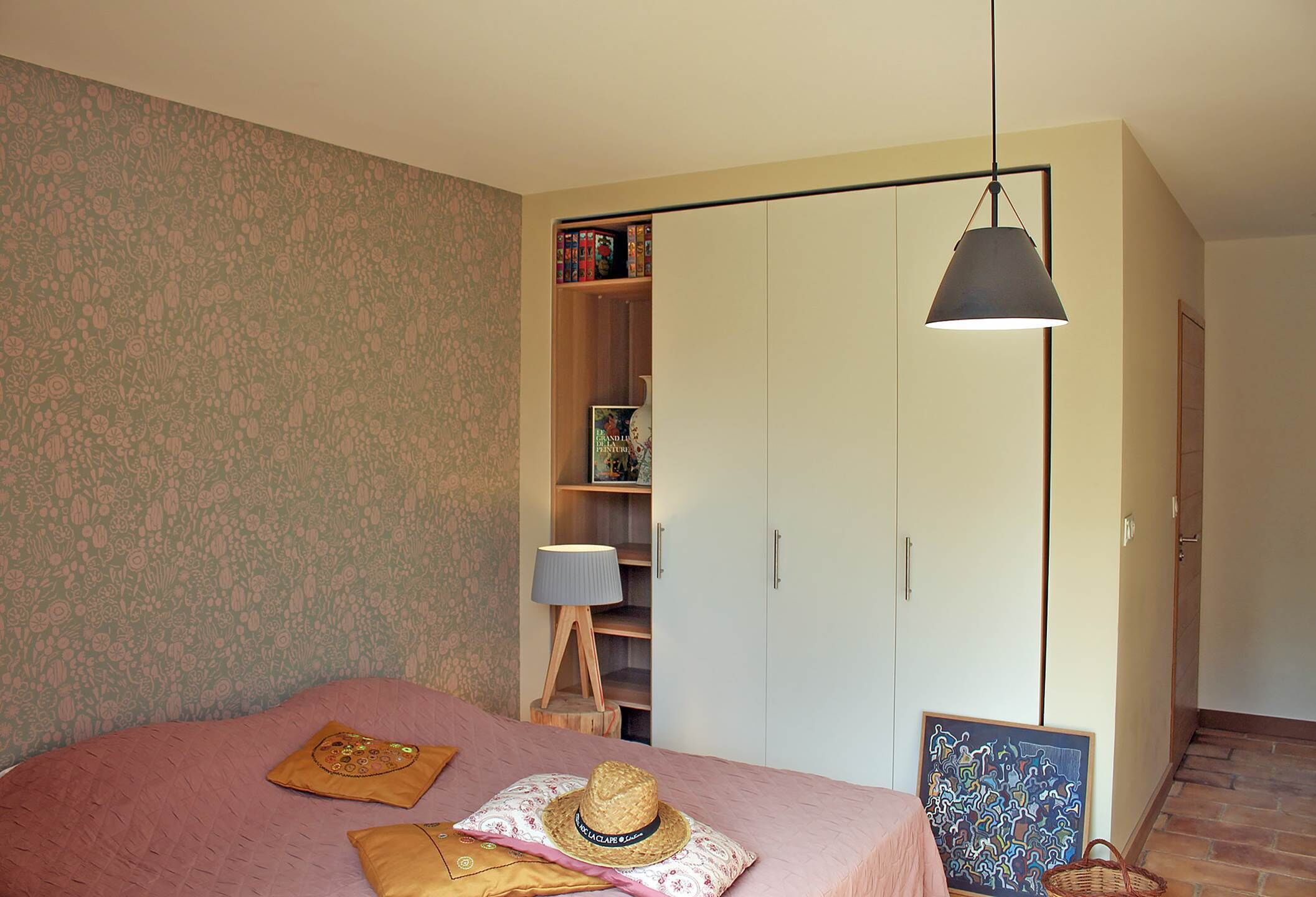 Un dormitorio con cama, armario, lámpara y un marco de fotos.