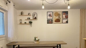 A dining area with a wooden table and bench, surrounded by shelves with decorative items and framed artwork on the wall.