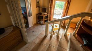 Eine Treppe führt zu einem Balkon mit einem Fernseher und einem kleinen Tisch.