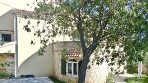 Ein Gebäude mit einer Stein-Fassade, einem Ziegeldach und einem kleinen Fenster mit grünen Fensterläden.