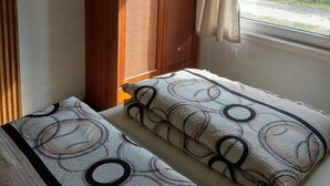 Um quarto com cama, guarda-roupa e janela com cortinas.