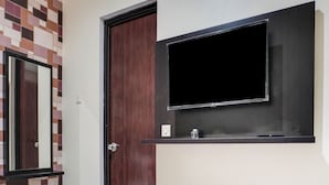 Een kamer met een houten deur, een spiegel en een wandtelevisie.