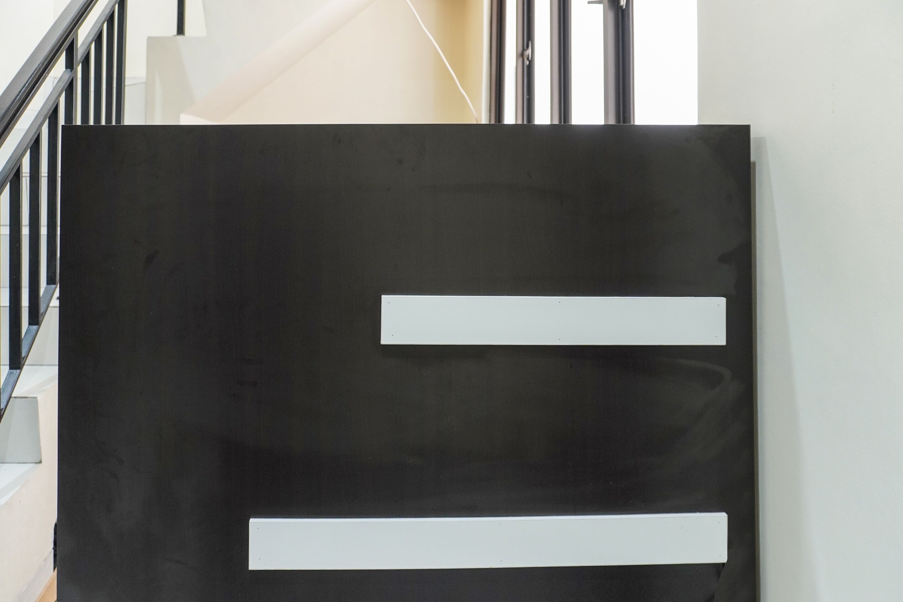 A modern interior with a staircase and a large black panel with white labels.