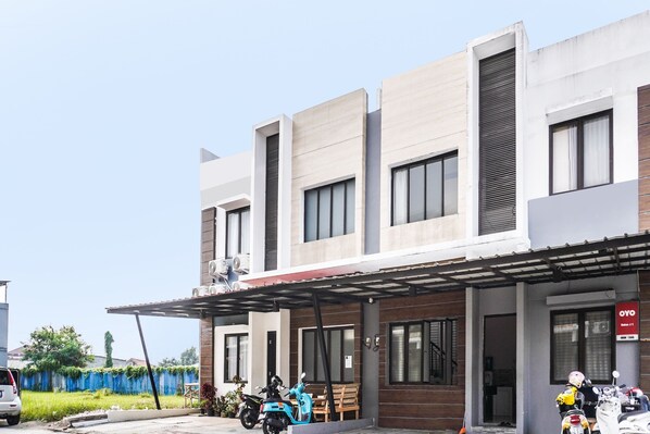 A modern building with a covered entrance, a blue scooter, and a motorcycle parked outside.