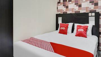 A bed with a white and red bedspread, two red pillows with "OYO" text, and a headboard with a black frame.