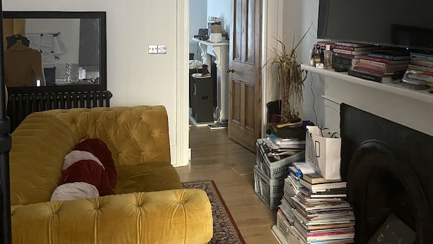 Ein Wohnzimmer mit gelbem Sofa, Kamin und Fernseher.