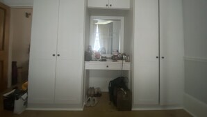 Ein begehbarer Kleiderschrank mit Spiegel, ein Schminktisch mit Pflegeprodukten und ein Schuhregal.