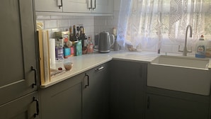 Eine Küche mit grauen Schränken, einem Spülbecken und verschiedenen Küchenutensilien auf der Arbeitsfläche.