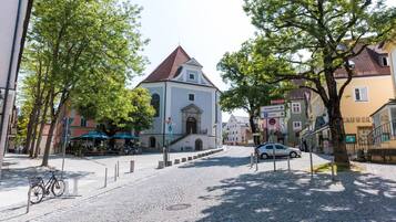 A cobblestone street with a church, a café, and a car parked on the side.
