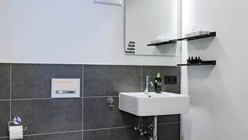 A modern bathroom with a white toilet, a white sink, and a mirror above the sink.