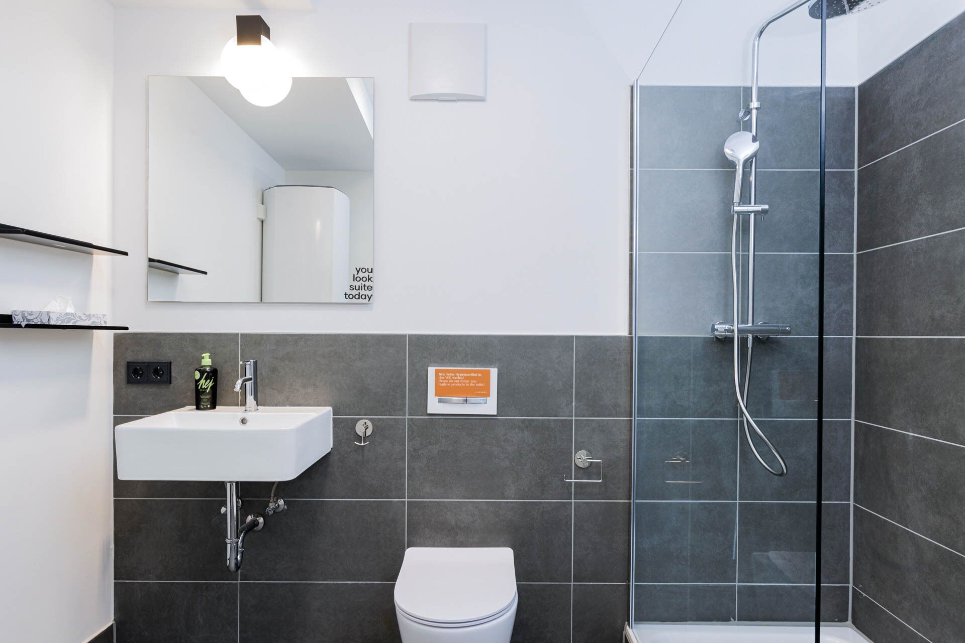 Une salle de bain moderne avec un lavabo blanc, des toilettes et une douche à parois de verre.