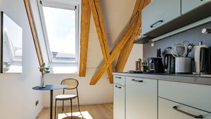 Une cuisine compacte avec un coin repas, dotée d’une fenêtre, de poutres en bois et d’appareils électroménagers modernes.