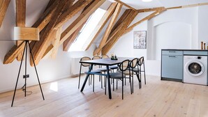 Une cuisine moderne avec des poutres en bois, un coin repas avec une table et des chaises, et un lave-linge.