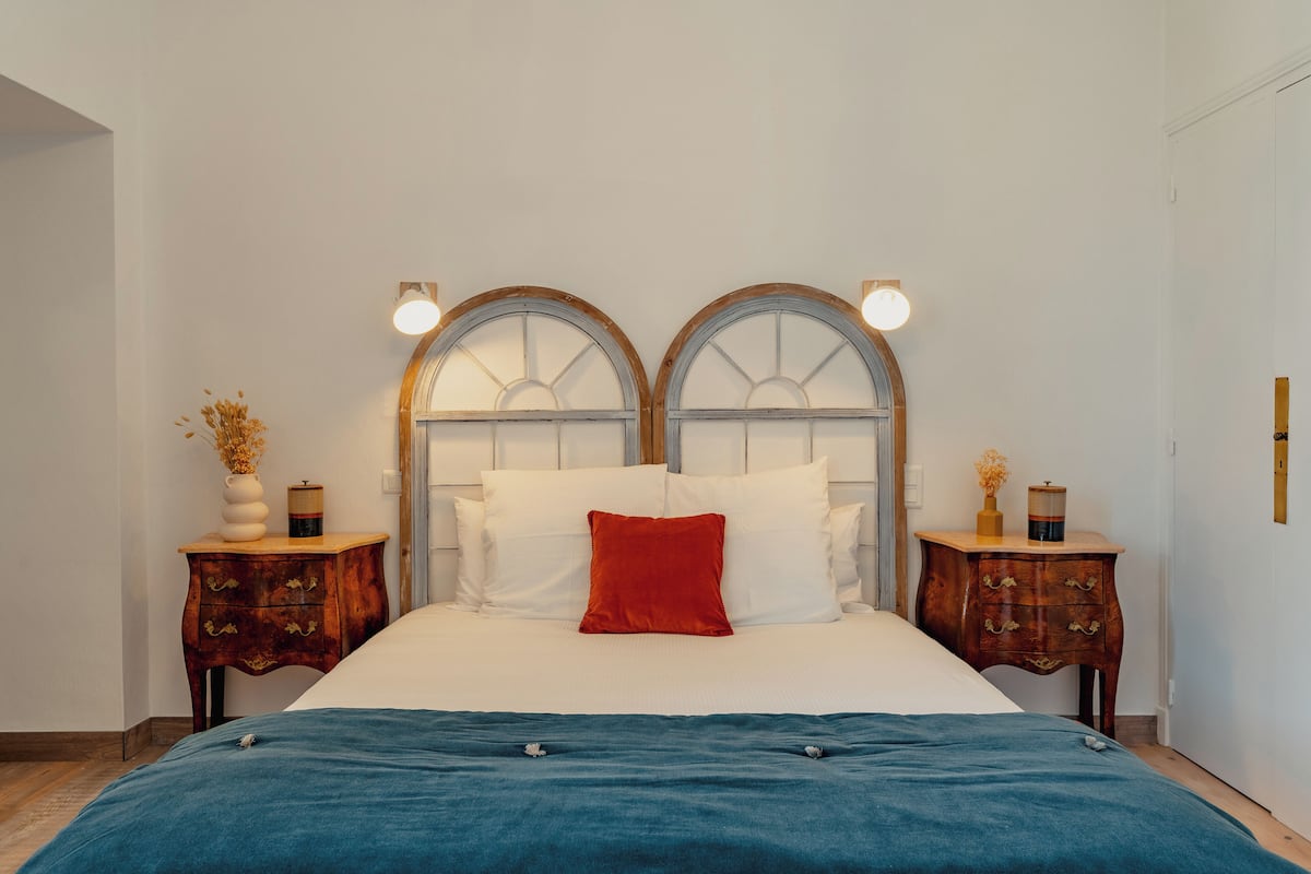 A bedroom with a large bed, two nightstands, and a wooden headboard with arched windows.