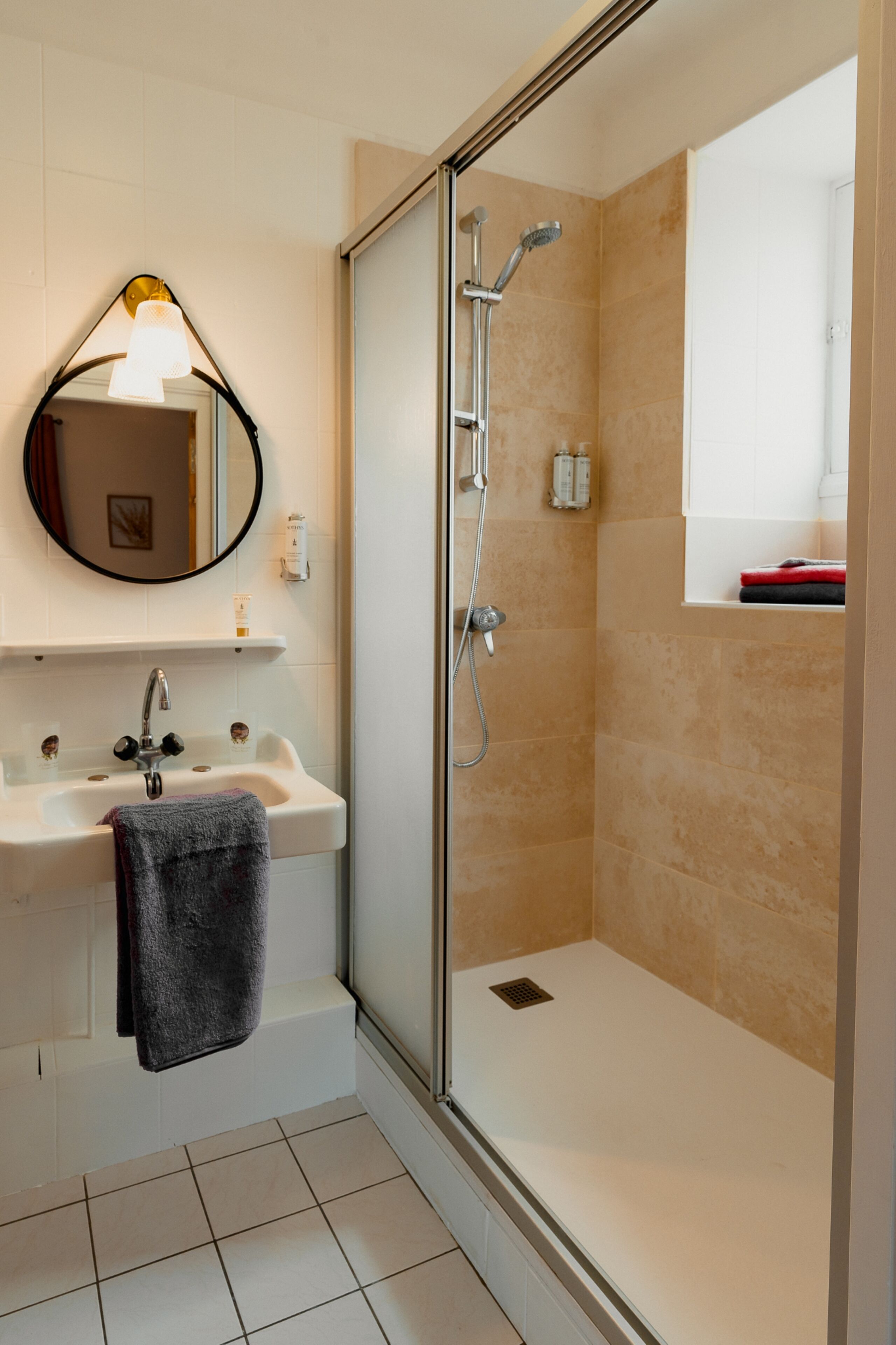A bathroom with a glass-enclosed shower, a sink with a towel, and a mirror.