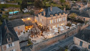An aerial view of a historic building with a courtyard, outdoor seating, and a swimming pool. - Hotel L'abbaye (Saint-Cyprien)