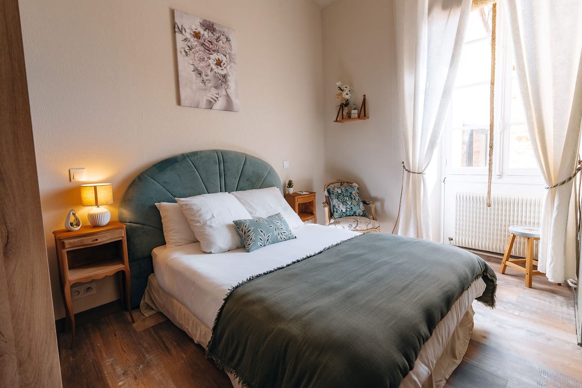A neatly arranged bedroom with a bed, bedside table, lamp, and a chair.