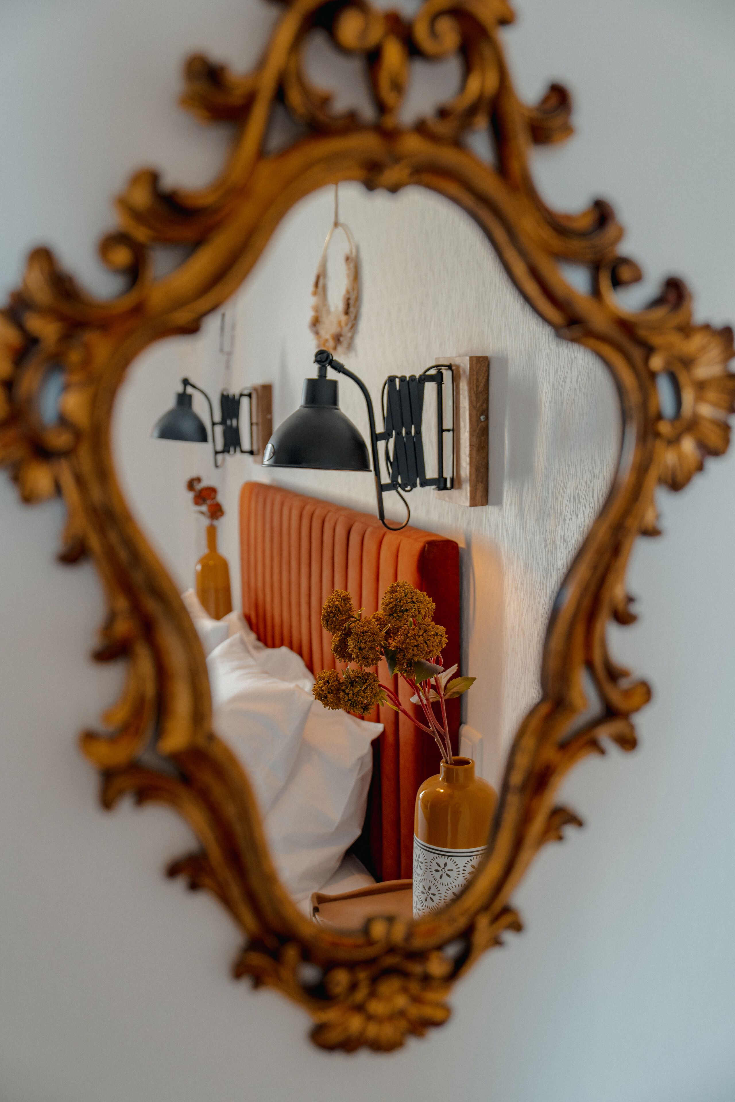 A room with a bed, a mirror, a radiator, and wall-mounted lamps.