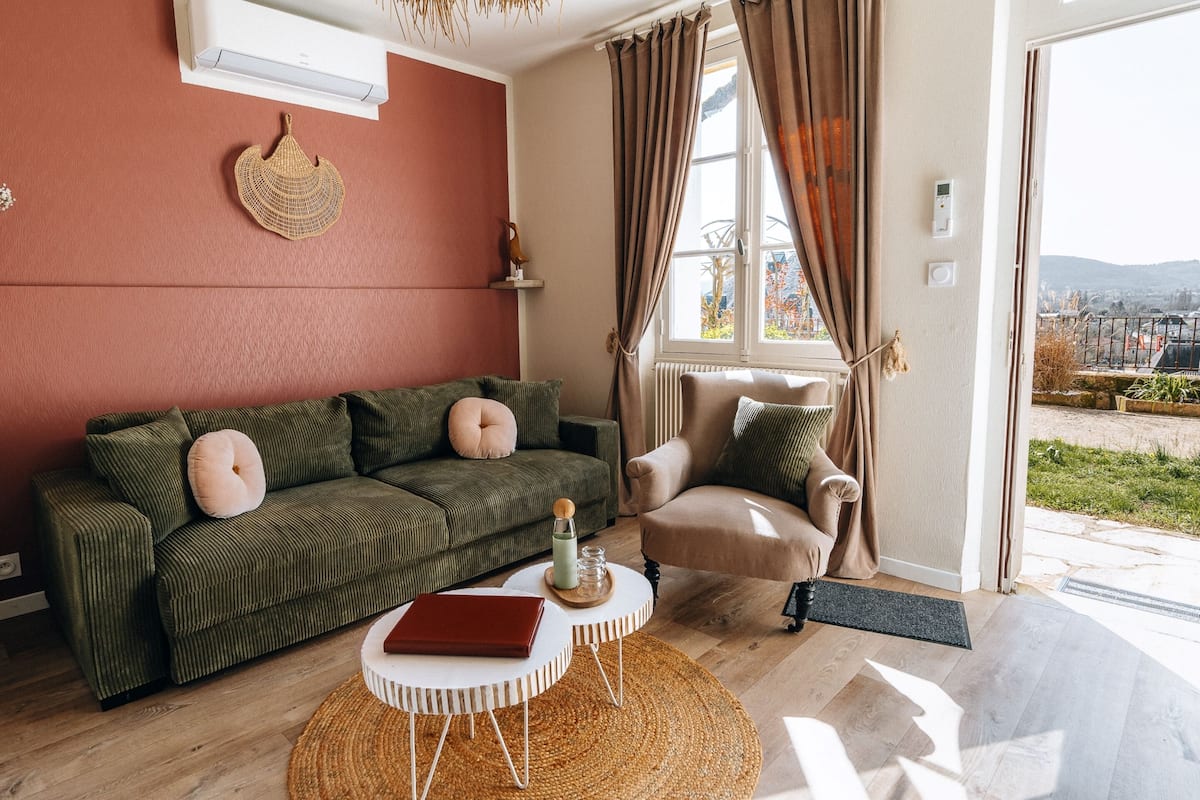 A living room with a green sofa, a beige armchair, and a small white table.