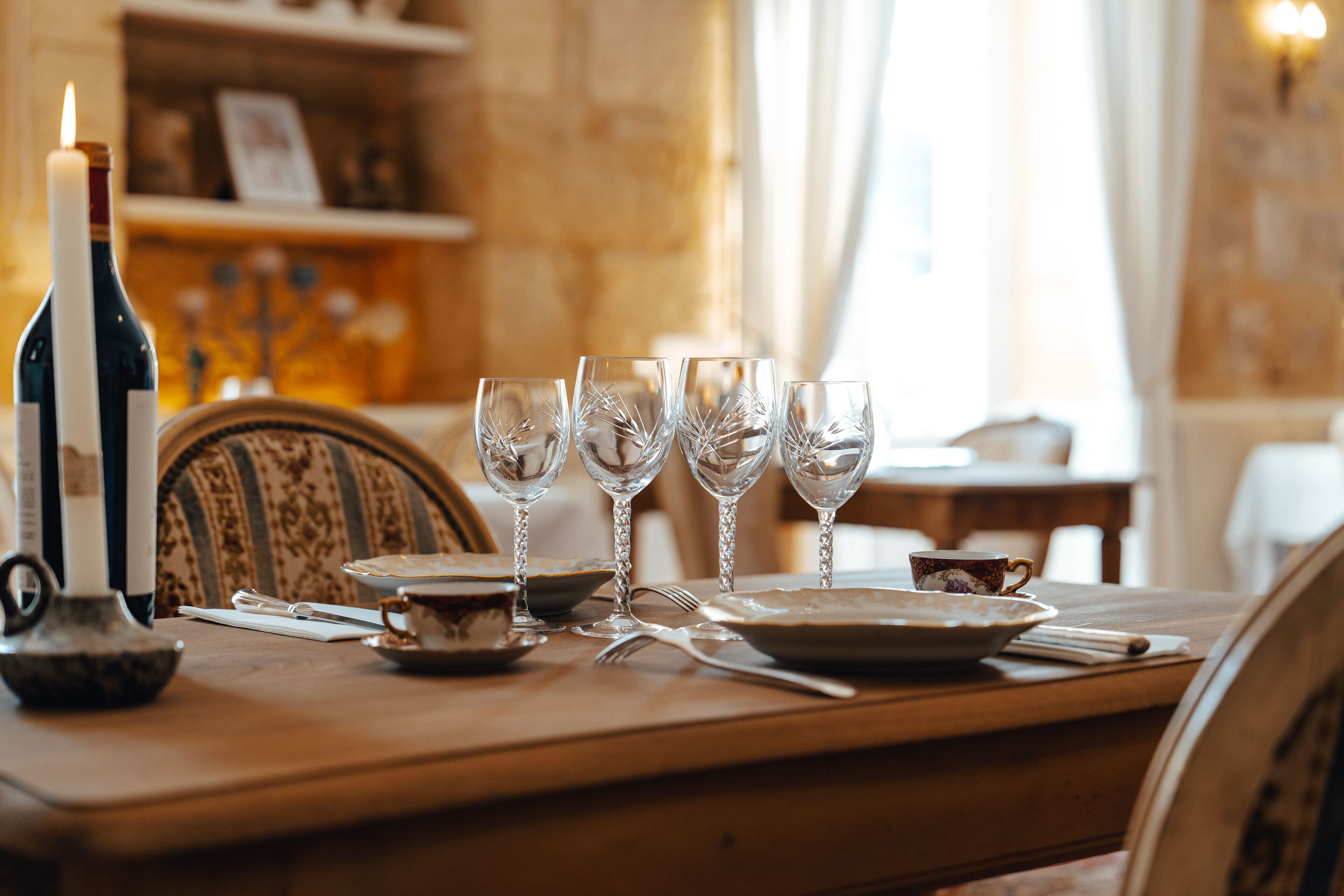 A dining table set with wine glasses, plates, and cutlery.