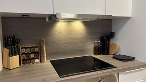 A modern kitchen with a built-in stove, wooden cabinets, and a spice rack.