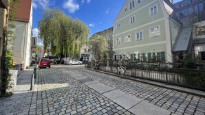 A cobblestone street lined with historic buildings, a bicycle, and a red car parked on the side.