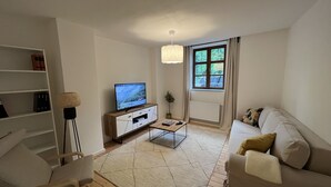 A modern living room with a TV, sofa, coffee table, and bookshelf.