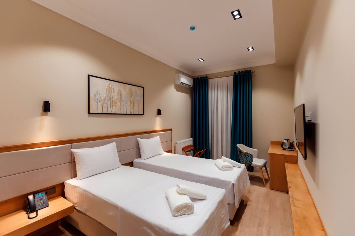 A hotel room with two beds, a desk, a chair, a phone, and a TV.