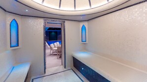 Um quarto de spa moderno com teto circular, uma banheira e duas janelas em arco.